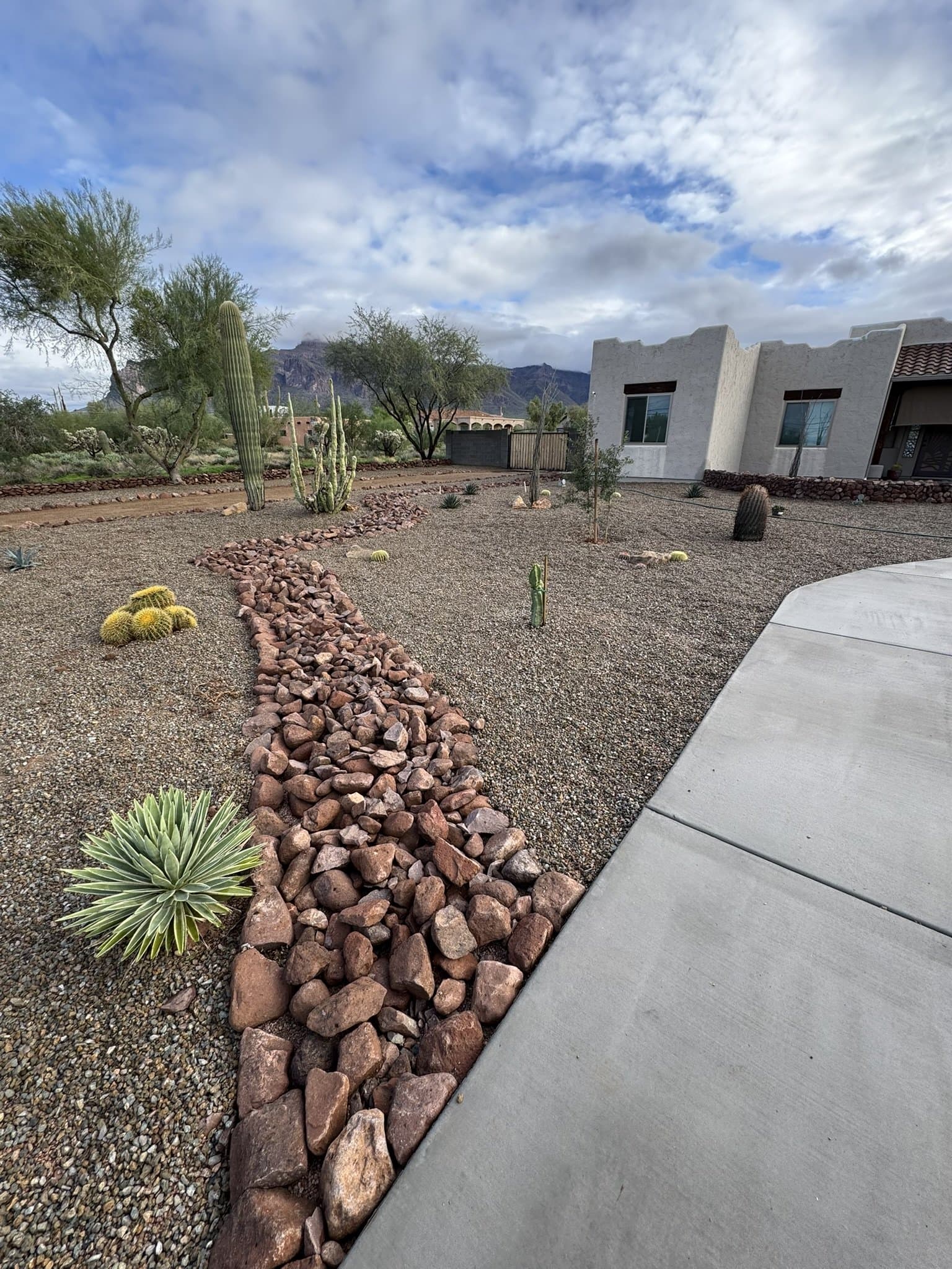 Desert front yard with a river rock dry creek bed, decomposed granite, barrel cactus and agave