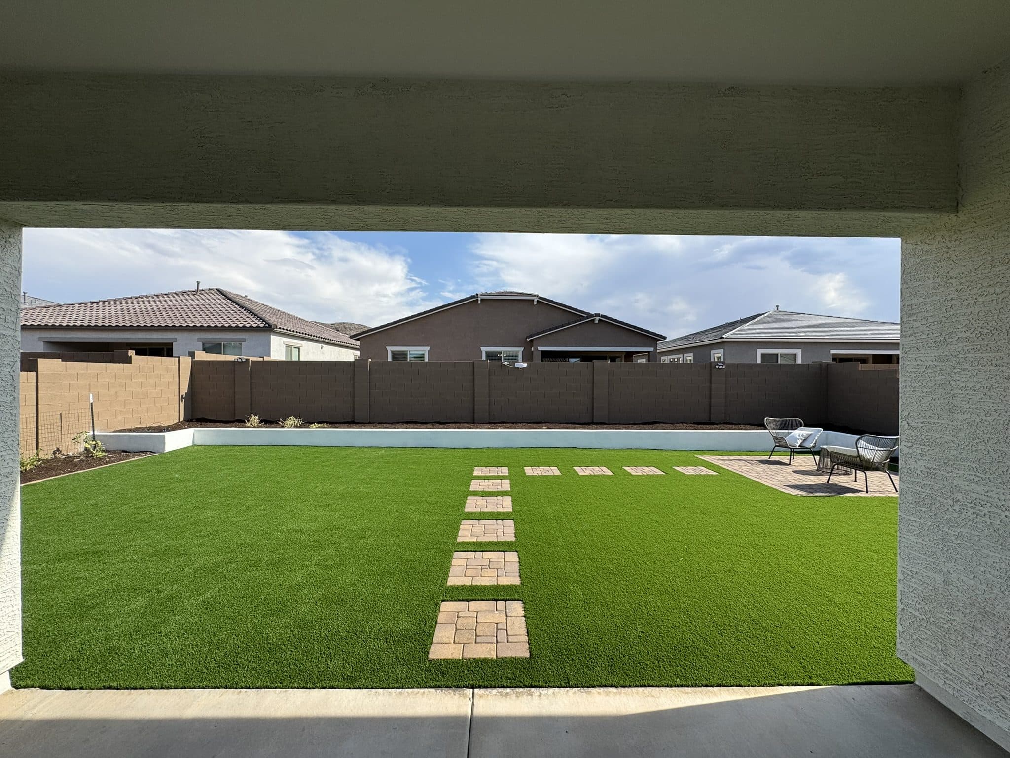 Turf lawn with a paver stepping-stone walkway viewed from the covered patio