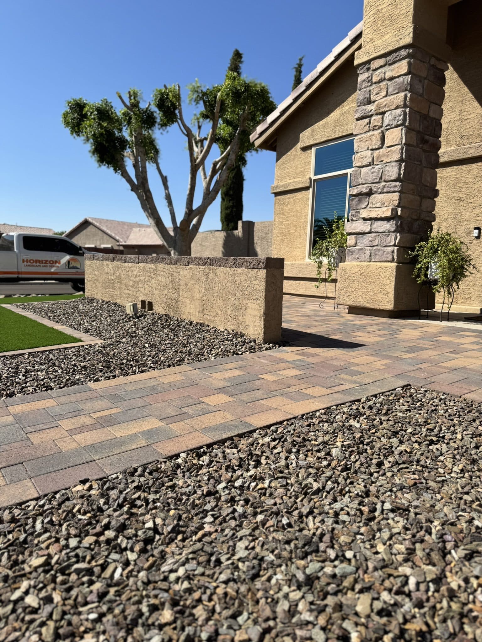 Belgard Dimensions 6 paver entry beside a stucco pony wall, turf and rock